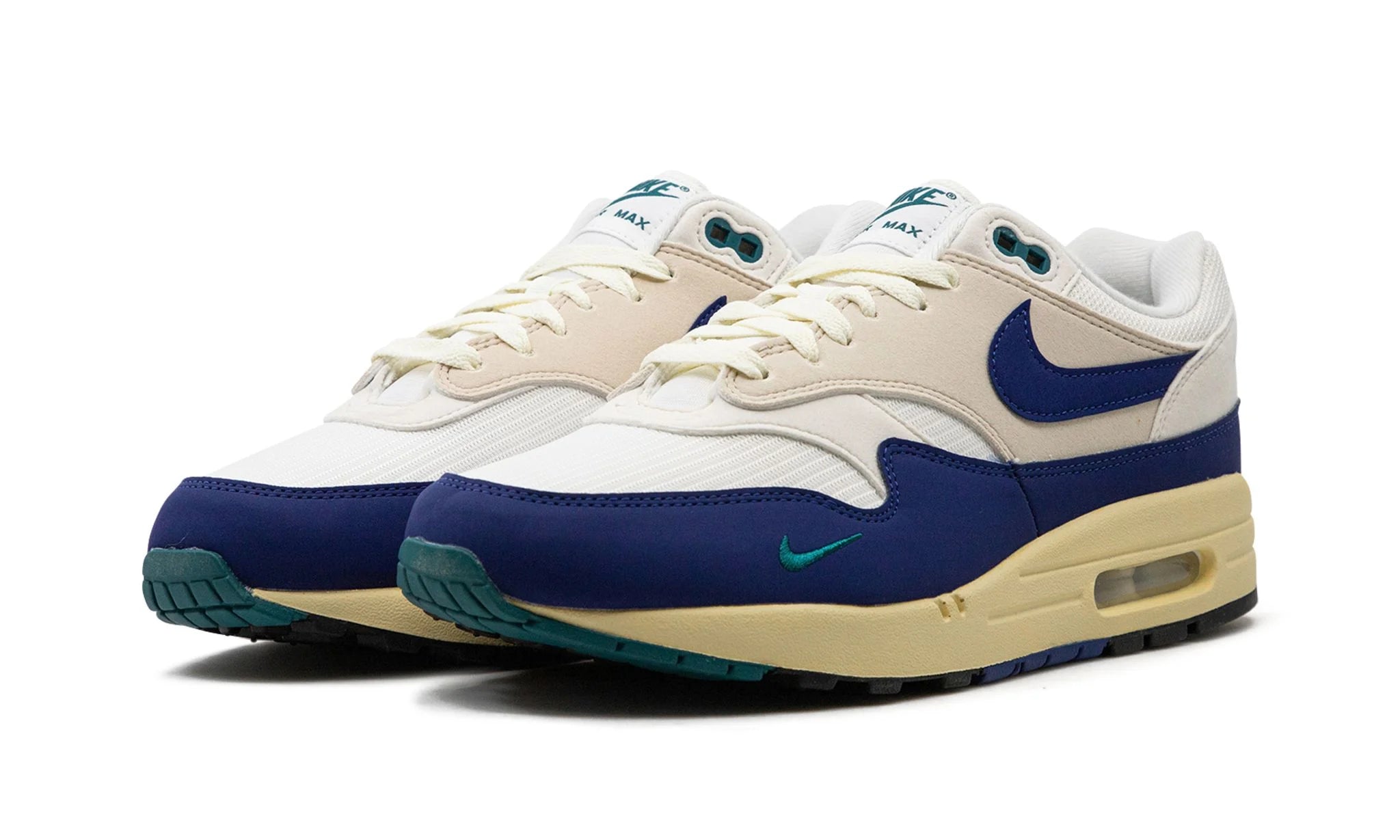 Nike Air Max 1 “Athletic Department Deep Royal Blue” (FQ8048) sneakers met een witte en lichtgrijze basis, gecombineerd met diepe royal blue accenten, premium mesh en suède overlays, en de iconische zichtbare Air unit in de zool.