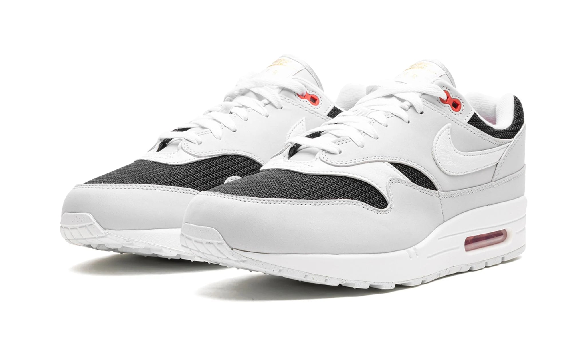 Nike Air Max 1 “Urawa 2023” (FD9081-001) sneakers met een grijze basis, bordeauxrode accenten en zwarte details, premium mesh en suède overlays, en de iconische zichtbare Air unit in de zool.