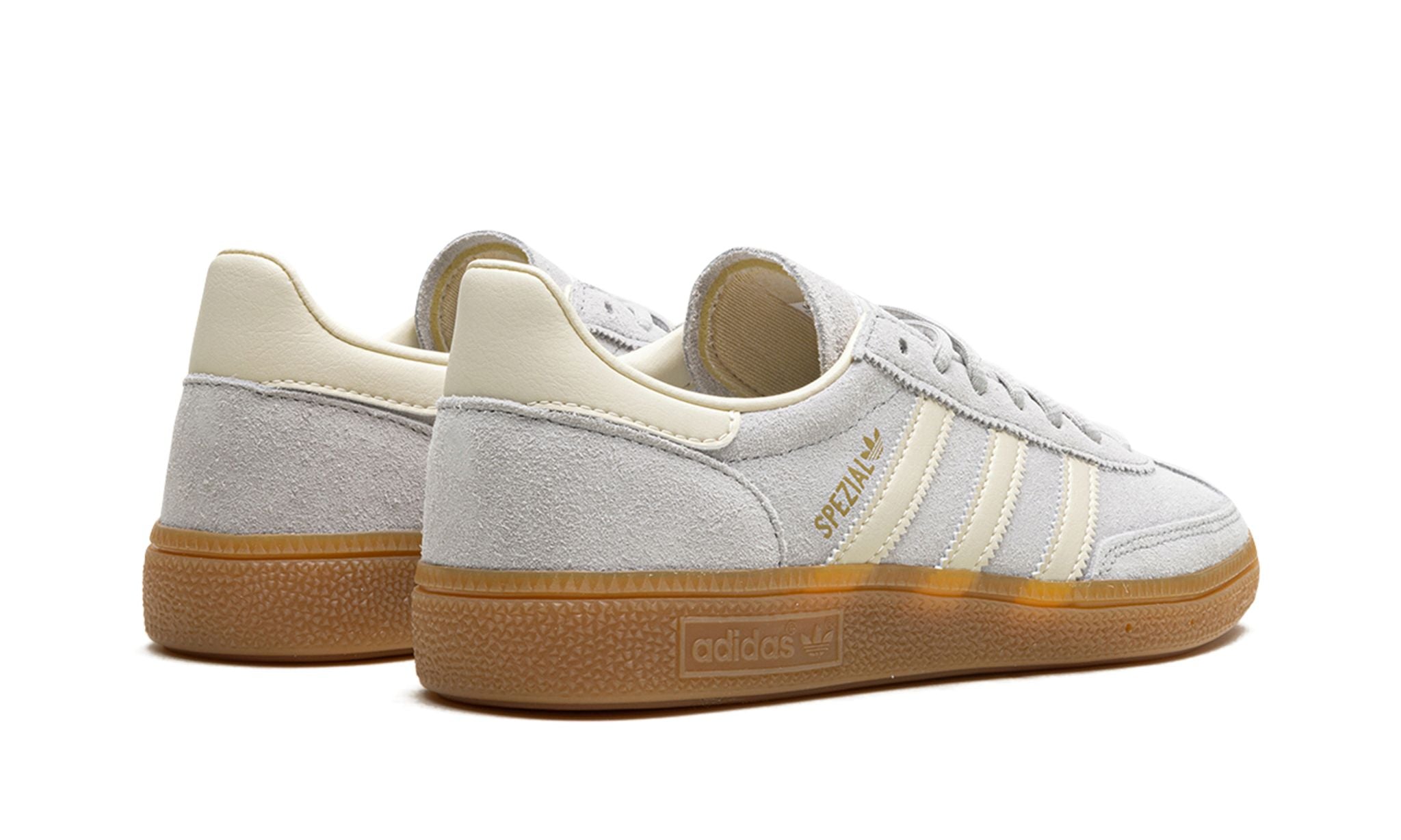 adidas Handball Spezial (IF7086) sneakers in een grijs en crème wit kleurenschema, uitgevoerd in zacht suède met de kenmerkende witte drie strepen, gum rubber zool en een klassiek low top retro silhouet.
